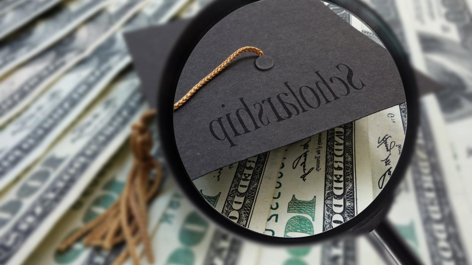 一叠美元和一顶写着“奖学金”的帽子。.